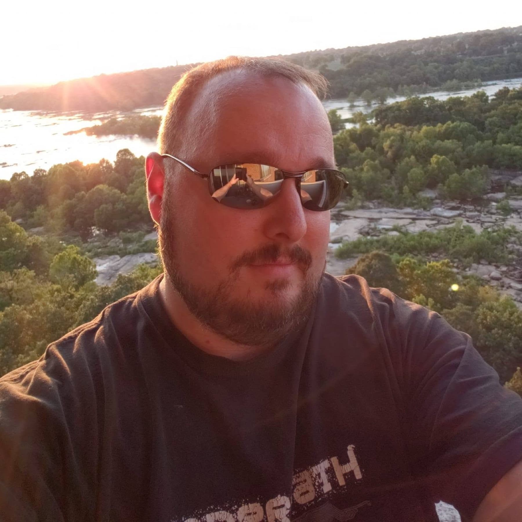 Jawa (Shawn, @JawaMeta) wearing sunglasses at sunset overlooking a river and trees